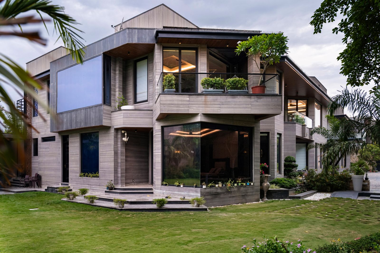 Angled exterior view of the twin residence highlighting grey stone cladding, projecting balconies and glass railings