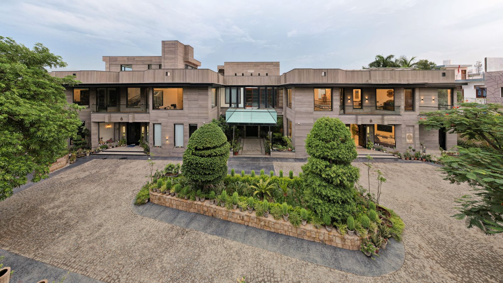 Elevated view of the residence showing its connected wings, landscaped courtyard and glass-covered terrace