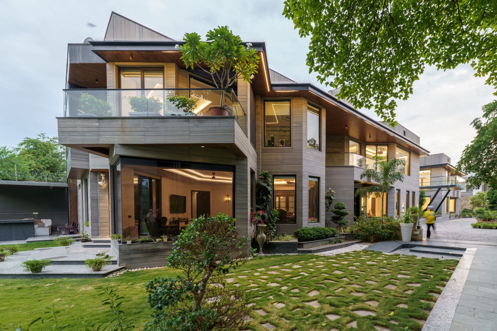 Contemporary twin residence in Agra with wood-finished facade, large glass windows and landscaped garden
