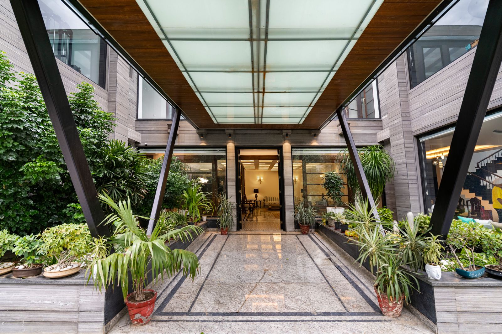 Covered entrance aisle with glass roof, timber soffit and planted borders at the Agra twin residence